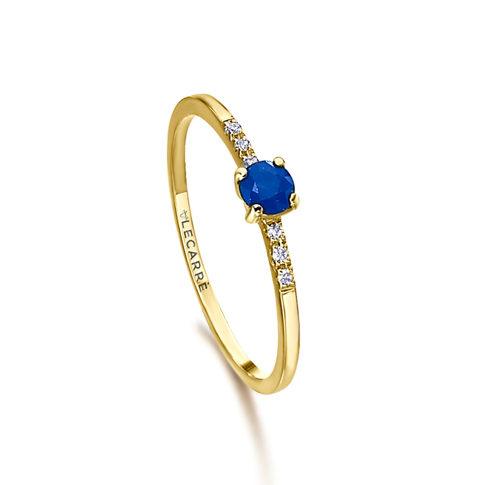 Solitaire ring in gold, with a central sapphire and diamonds on the band.